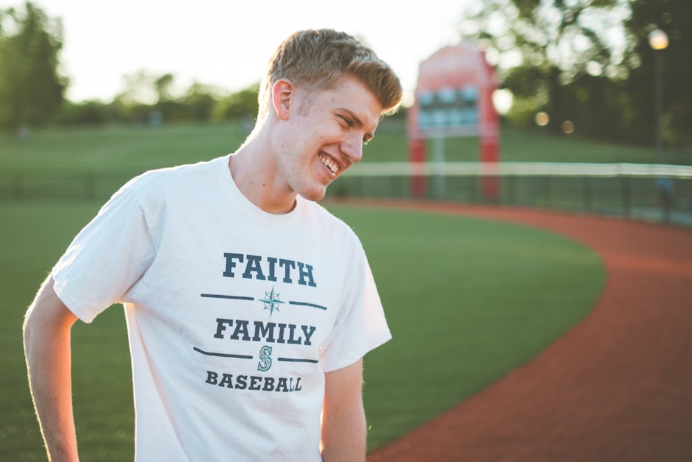 man in white crew neck t-shirt standing on brown field during daytime