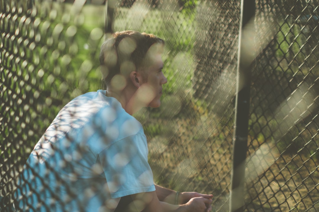 man in blue and white shirt sitting on brown wooden bench