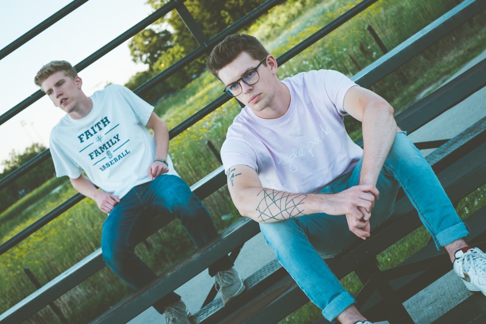 man in white crew neck t-shirt sitting on black metal bench