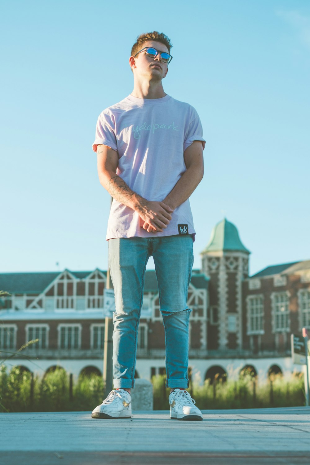 man in white crew neck t-shirt and blue denim jeans standing on green grass field