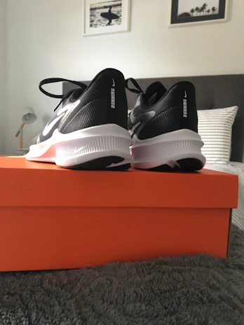 Modern black and white running shoes positioned on a neutral-toned floor.