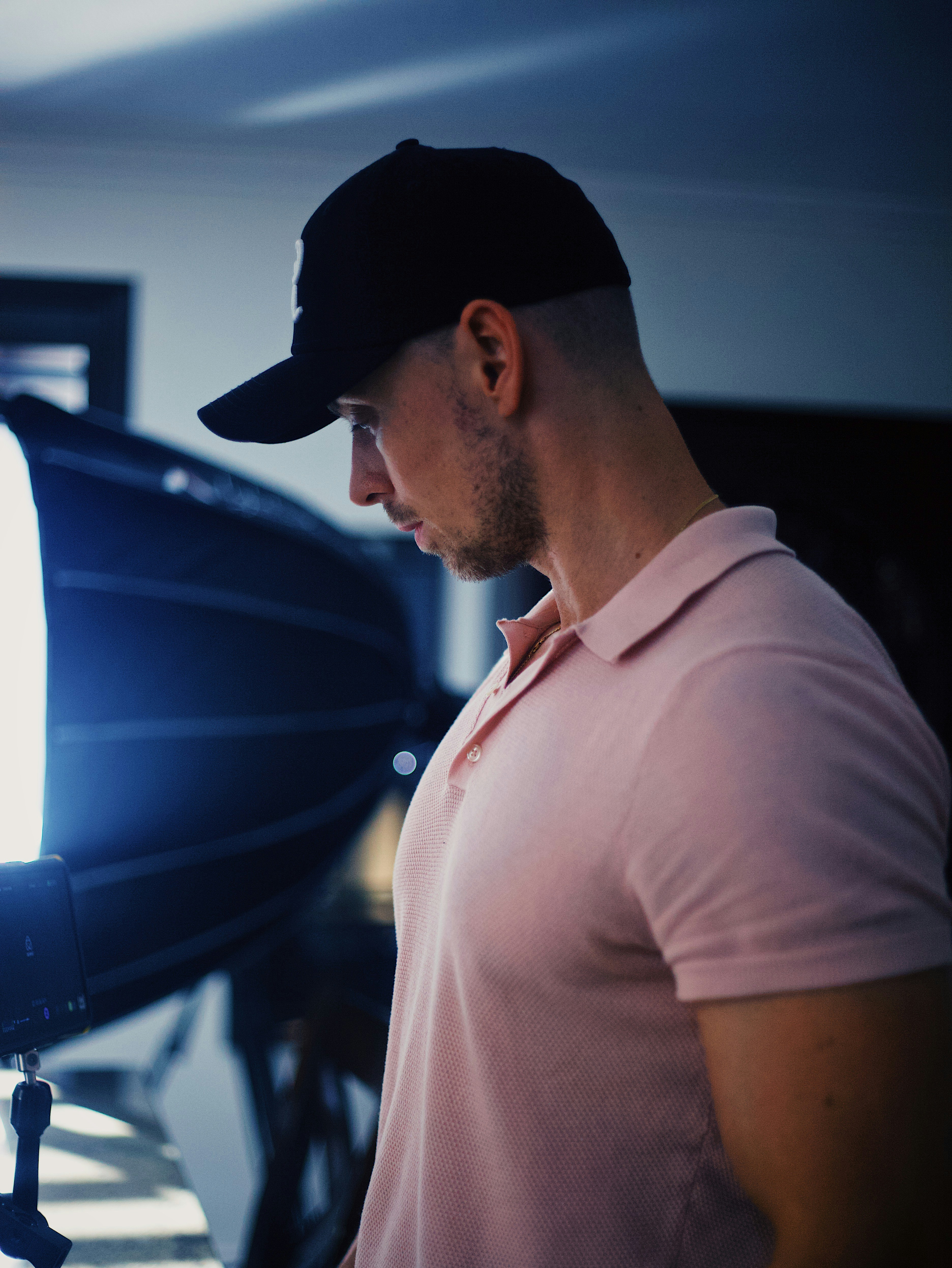 man in white polo shirt wearing black cap