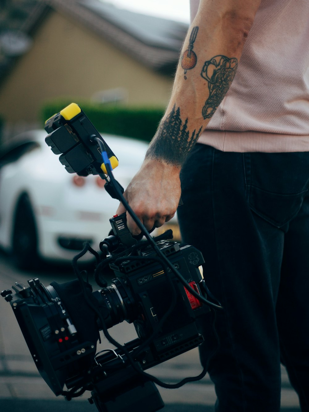 man in white tank top and blue denim jeans holding black video camera