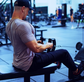 man in gray t-shirt and blue denim jeans sitting on bench