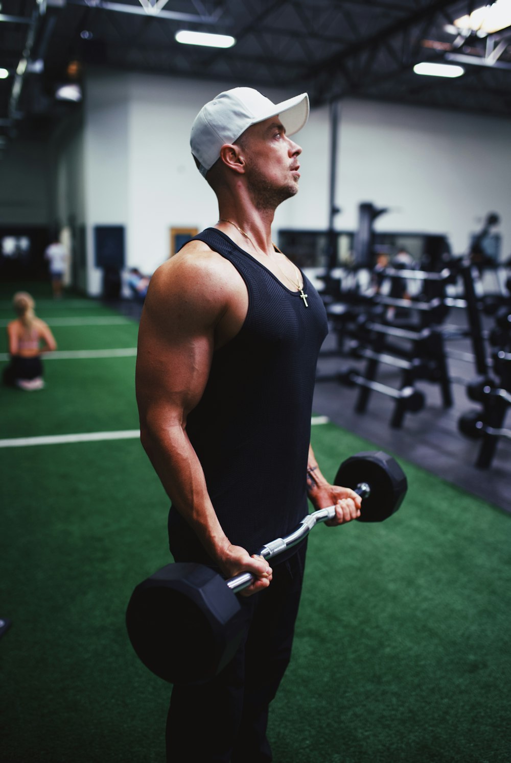 man in black tank top holding black dumbbell