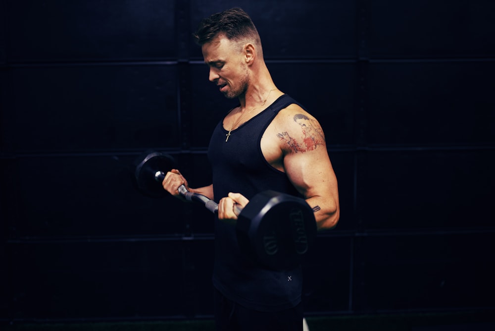 woman in black tank top holding dumbbell