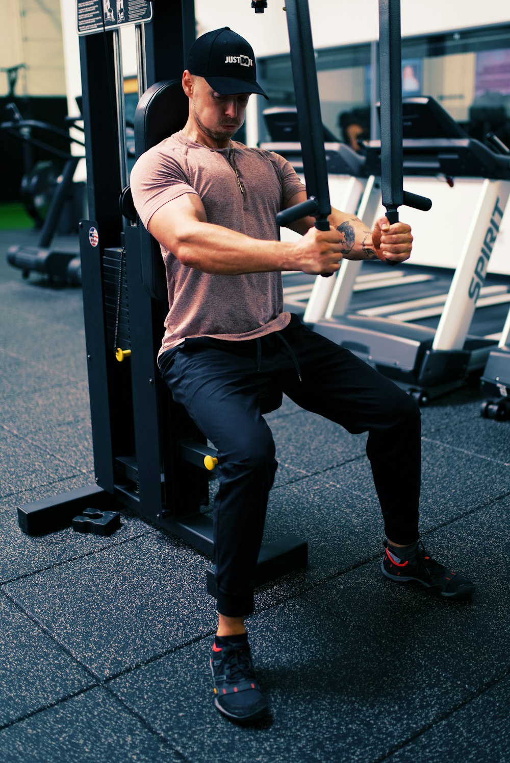 man in gray t-shirt and black pants sitting on black and white metal bar