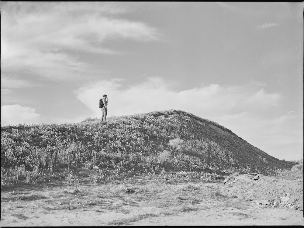 grayscale photo of man standing on hill