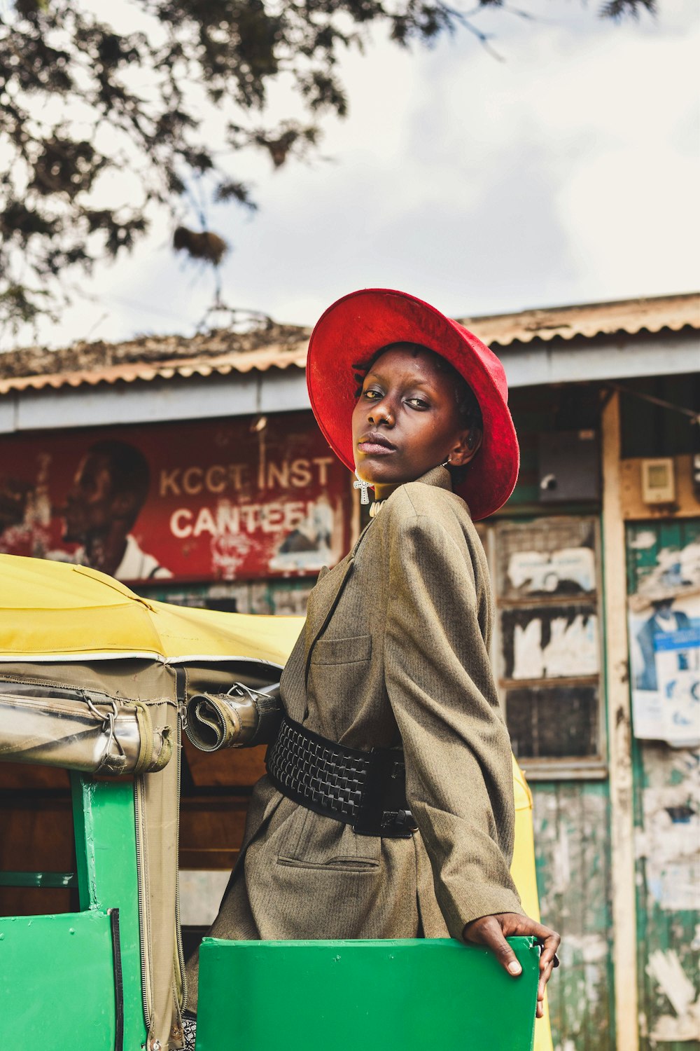 woman in green coat and red hat standing near cars during daytime