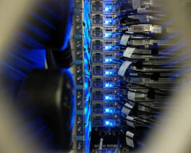 Close-up of hands installing network cables in a server rack with blue LED lights.