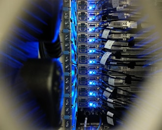 Network cables and servers illuminated with blue LED lights in a data center.