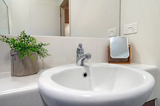 Modern bathroom with sleek ceramic sink and water-saving fixtures, surrounded by greenery.