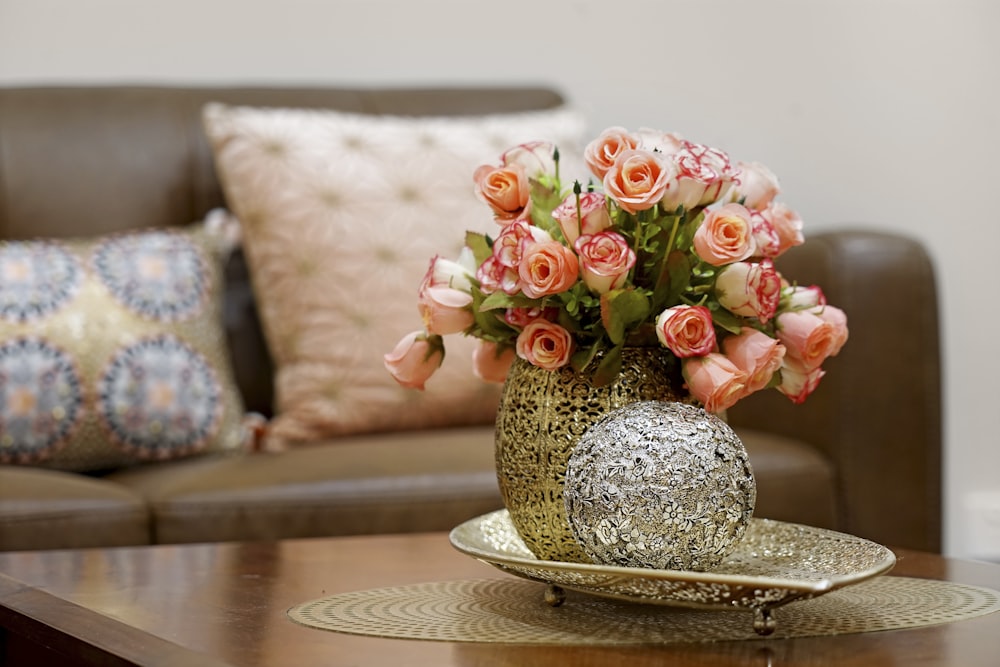 pink and white roses in brown ceramic vase on brown wooden table