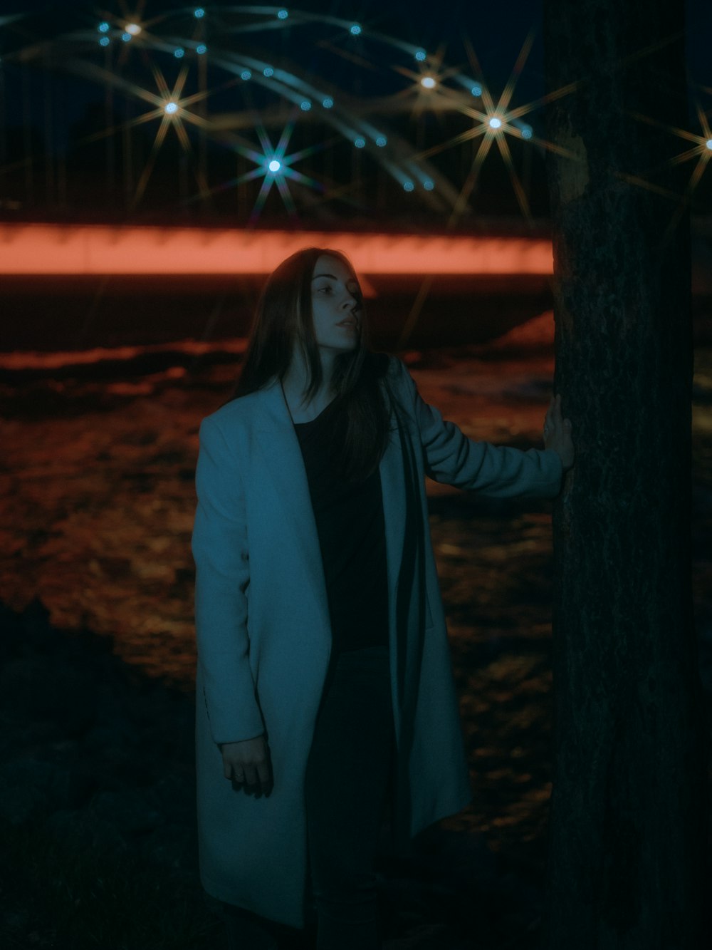 woman in black coat standing beside tree