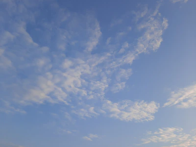 A clear blue sky with soft rays of sunlight filtering through light clouds, inspiring peace and transformation.