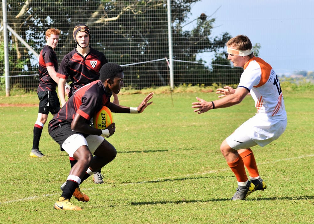 group of men playing soccer on green grass field during daytime