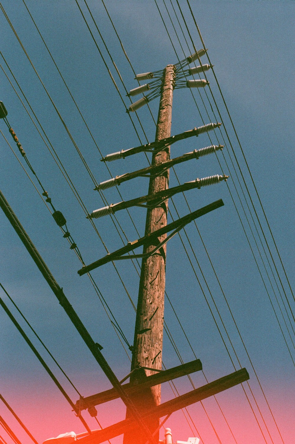 brown wooden electric post under blue sky during daytime