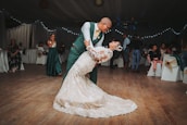 A joyful couple sharing their first dance surrounded by guests in a beautifully decorated hall.