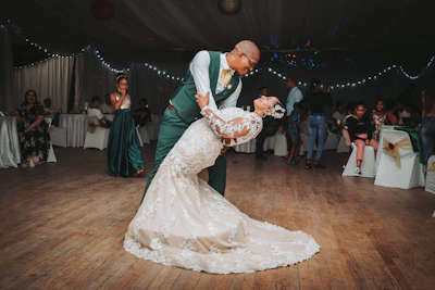 A couple sharing their first dance surrounded by smiling guests.