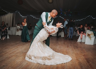 man in black suit jacket holding woman in white wedding dress