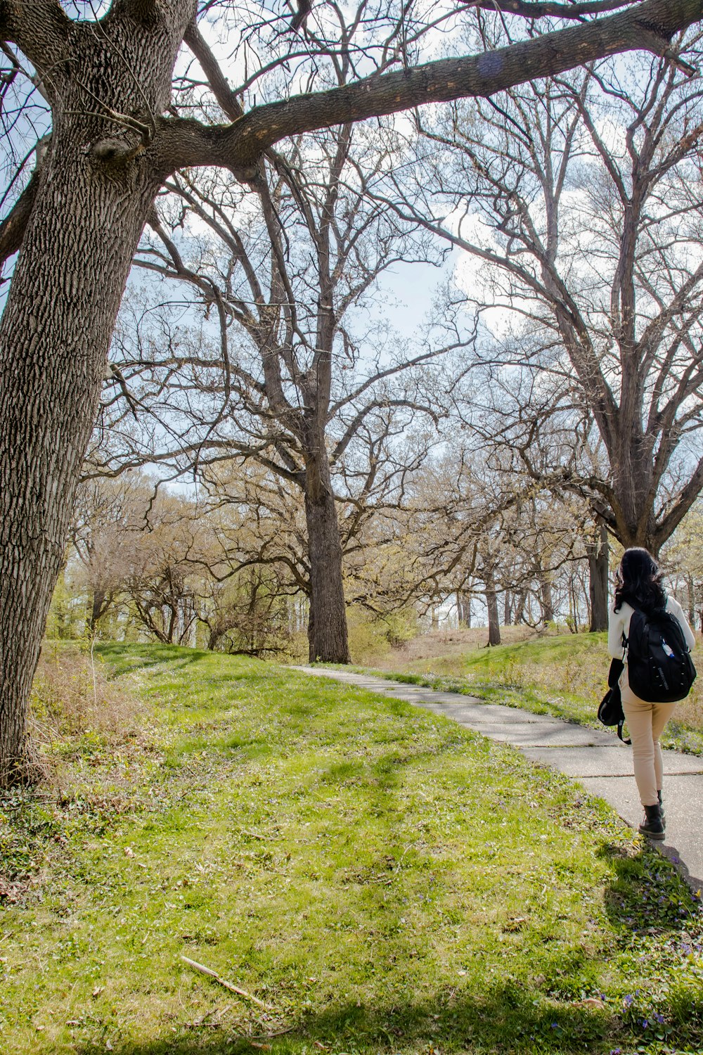 woman in black jacket walking on green grass field during daytime