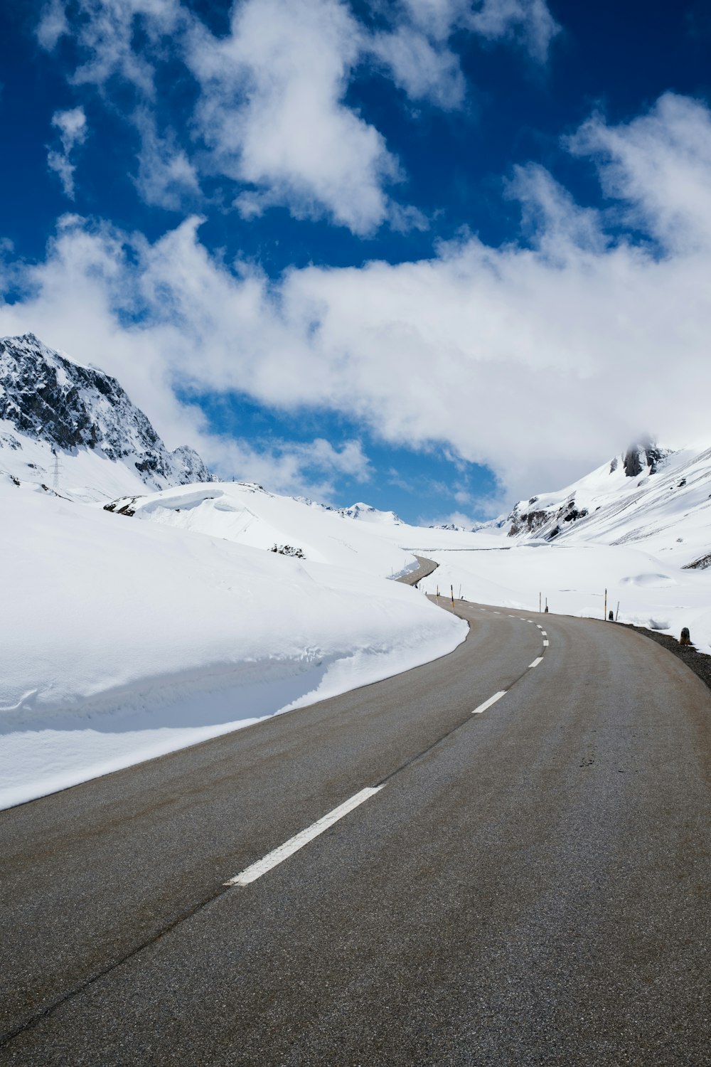 Graue Betonstraße in der Nähe eines schneebedeckten Berges unter blauem Himmel tagsüber