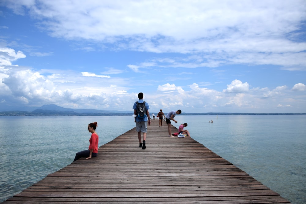 2 men and woman walking on wooden dock during daytime