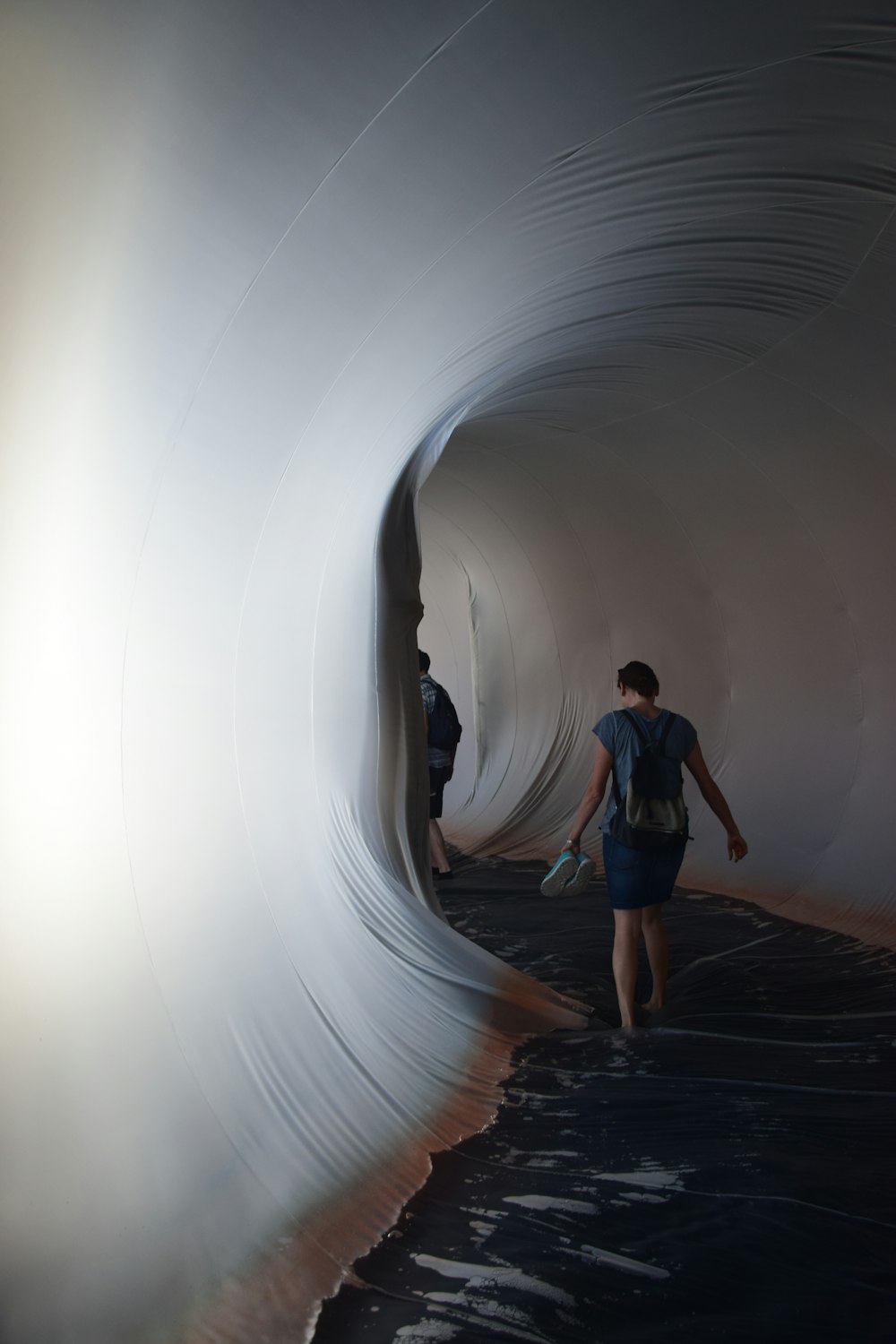 man in black t-shirt and blue denim jeans walking on tunnel