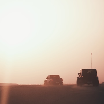An off-road vehicle climbing a rocky trail at sunset, dust trailing behind