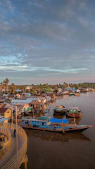 Historic riverside village scene with traditional Malay wooden houses and palm trees.
