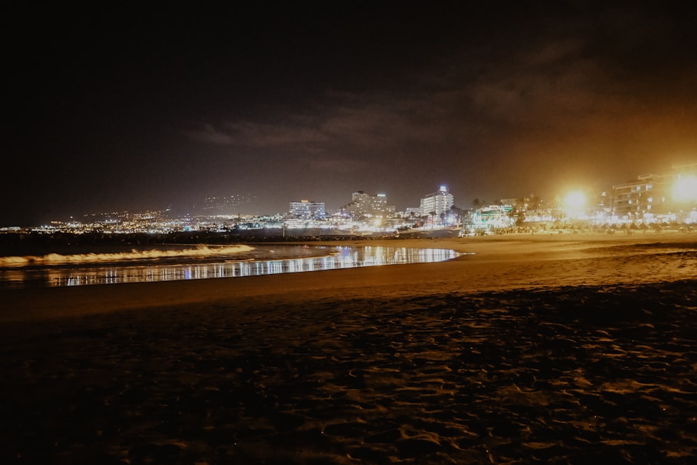 a night view of a beach with a city in the background