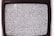 A close-up view of an old television screen displaying static noise. The screen is filled with a pattern of black and white dots and spots, typical of a signal loss or disturbance. The television set has a vintage design with a black frame.