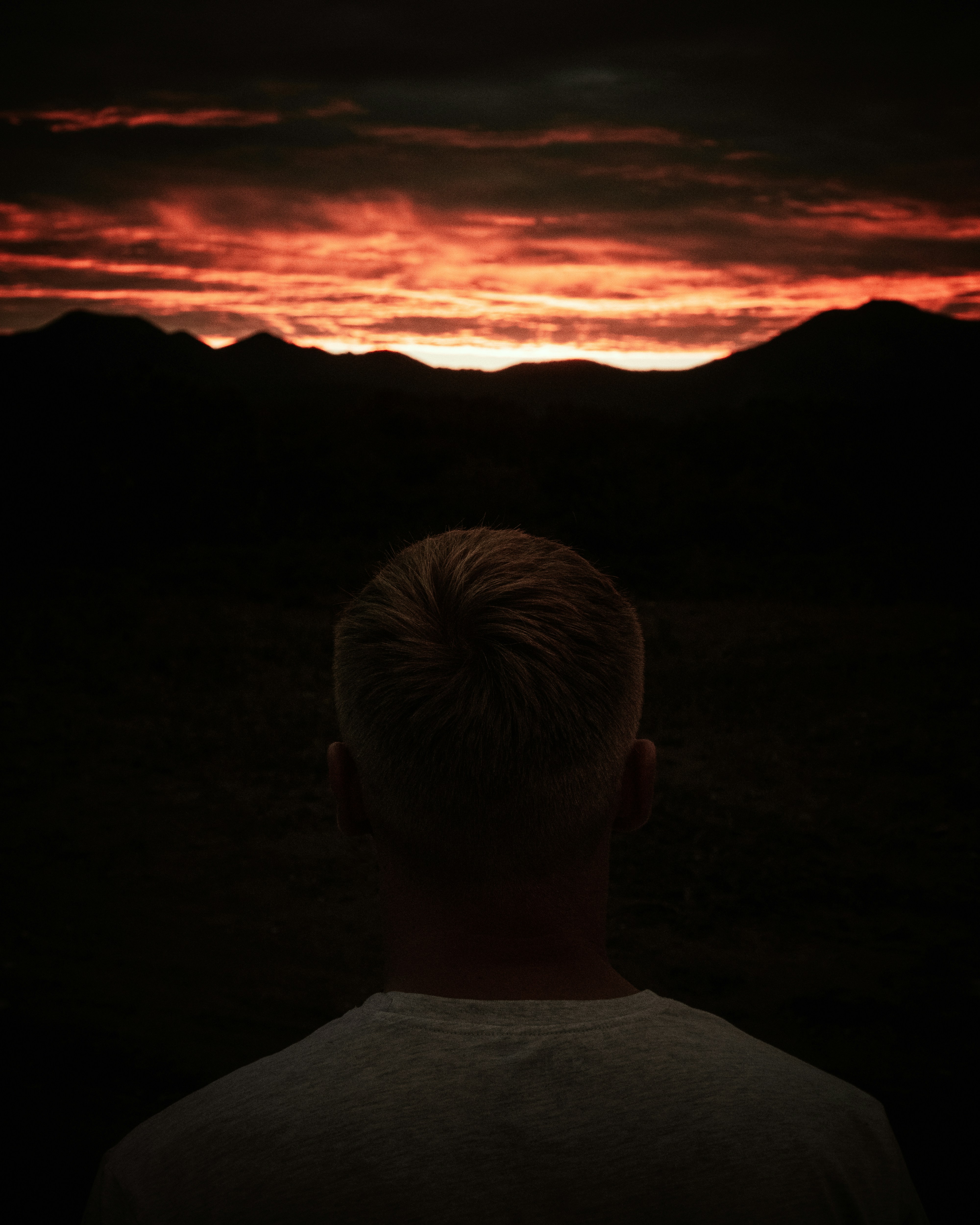 man in white crew neck shirt looking at the sunset
