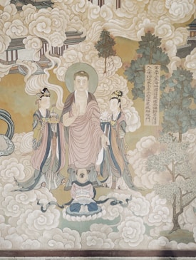 A traditional Asian-style painting featuring three figures adorned in ornate robes. The central figure appears divine or enlightened, holding one hand in a gesture of teaching. Surrounding them are swirling clouds, trees, and architectural elements suggestive of a heavenly realm. There is also an inscription in a vertical column, adding to the spiritual or historical context.