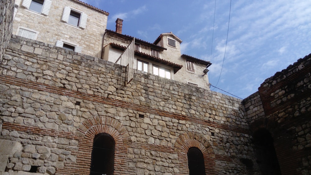 a stone wall with two windows and a clock on it