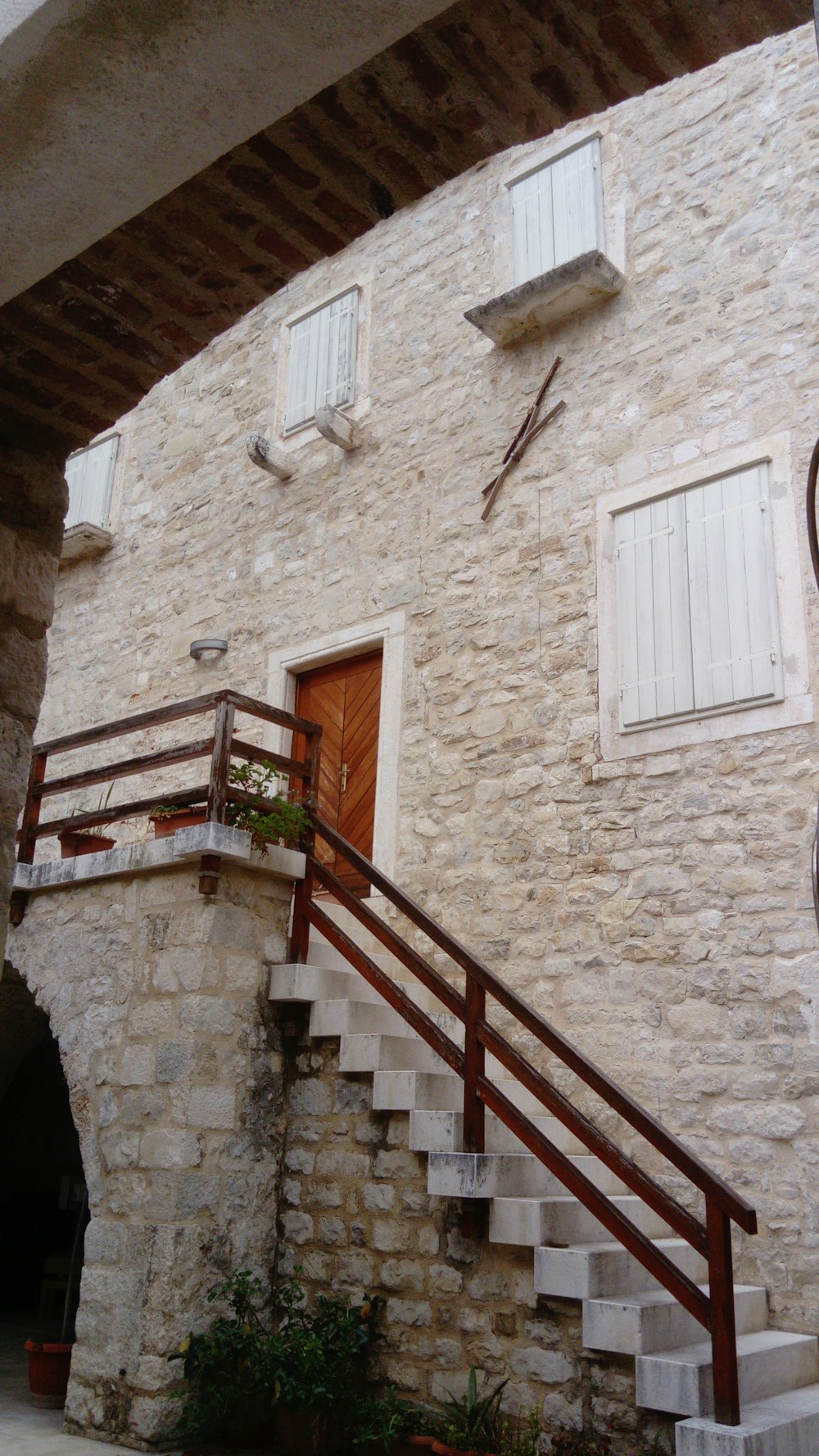 a stone building with white shutters and a wooden hand rail