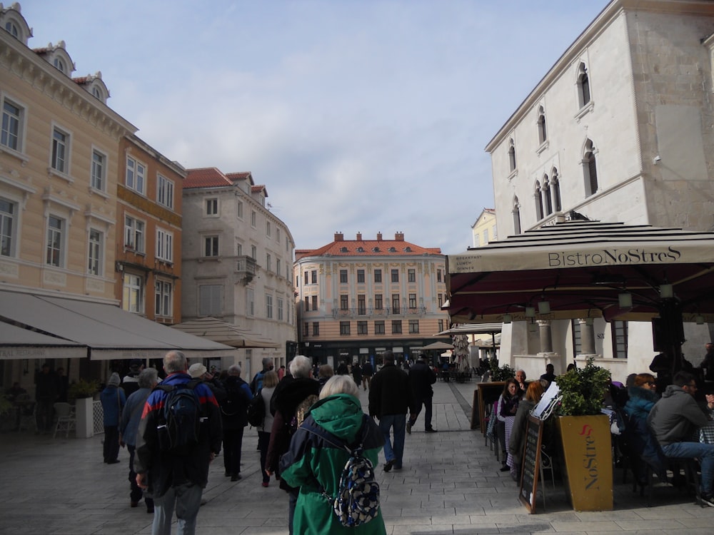 a crowd of people walking down a street next to tall buildings