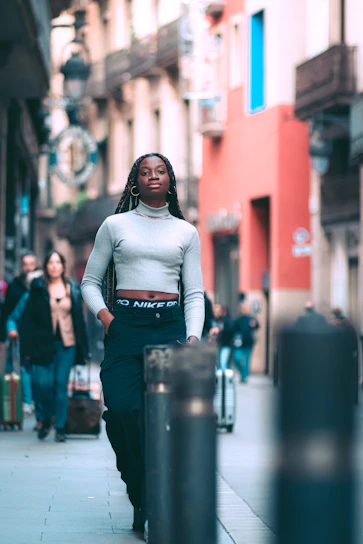 A young woman walking confidently down a city street wearing a soft, relaxed-fit hoodie and joggers in neutral tones.