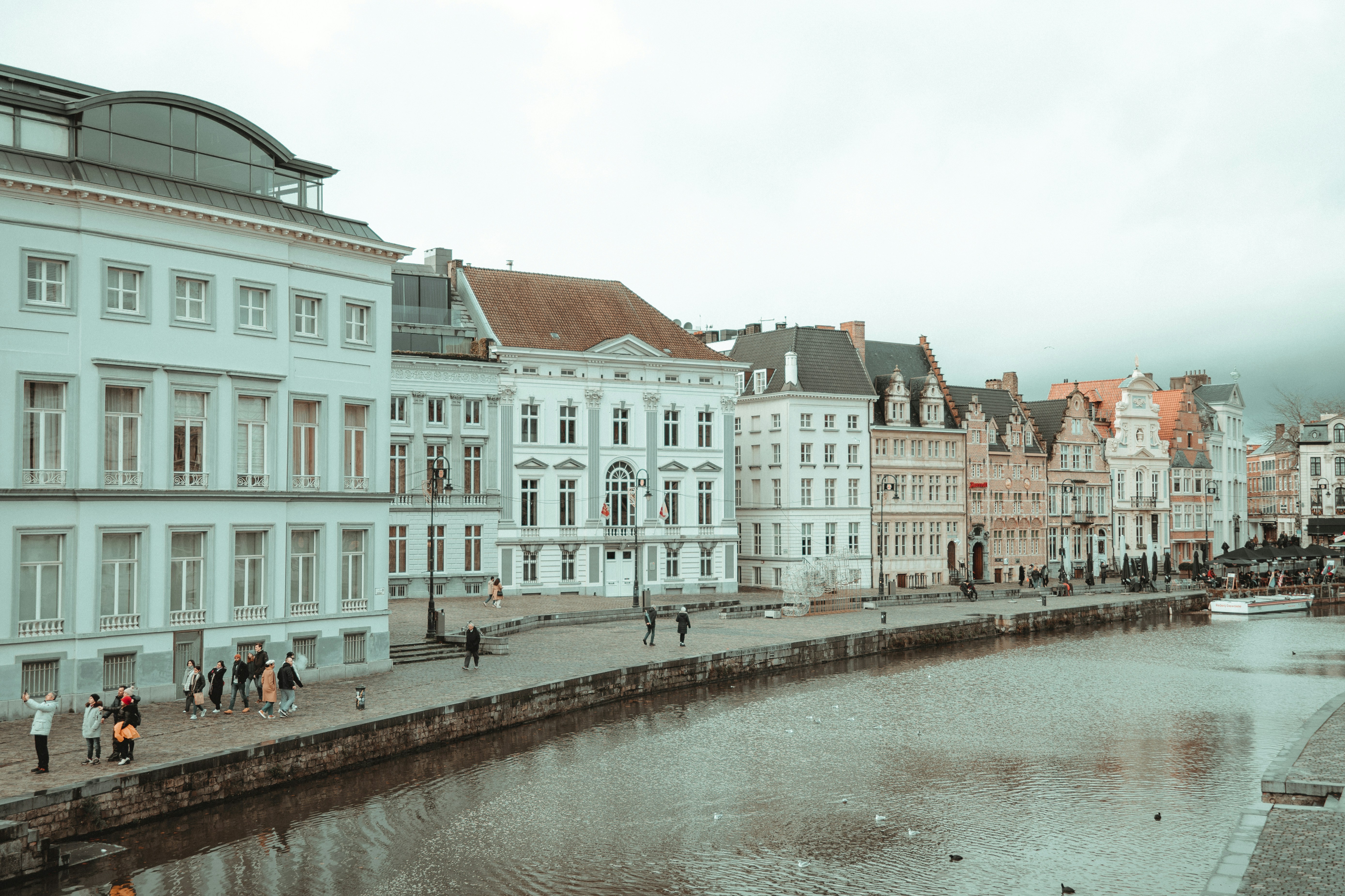a group of people walking down a street next to a river