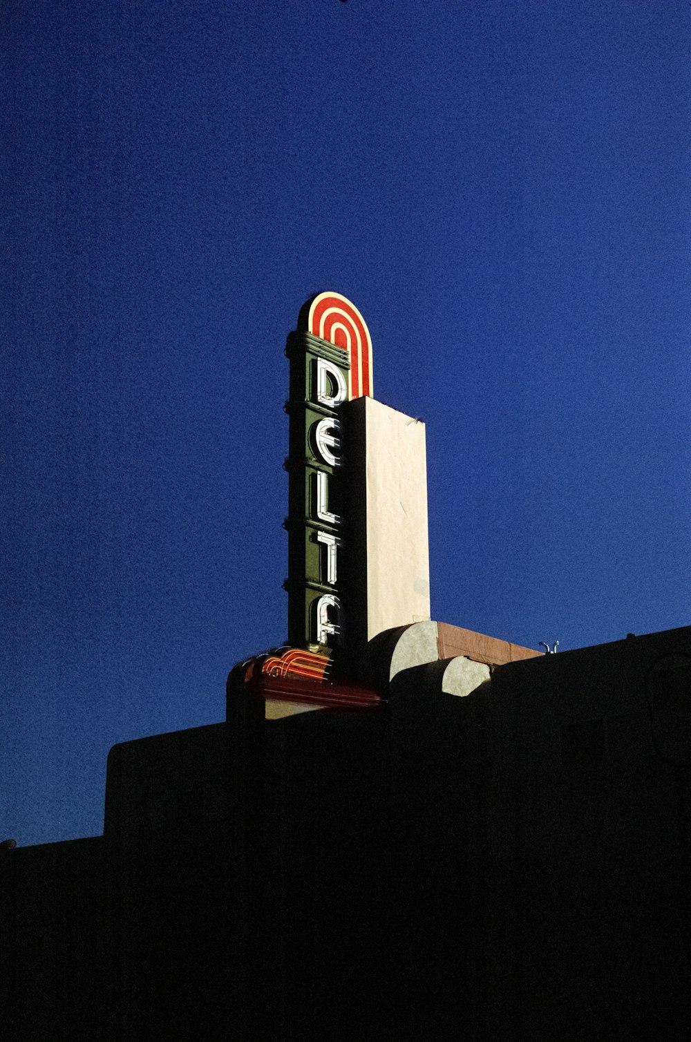 un cartello in cima a un edificio con un cielo blu sullo sfondo
