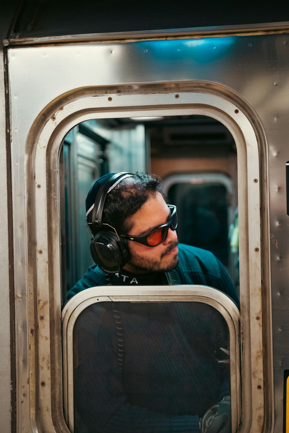 a man wearing headphones looking out the window of a train