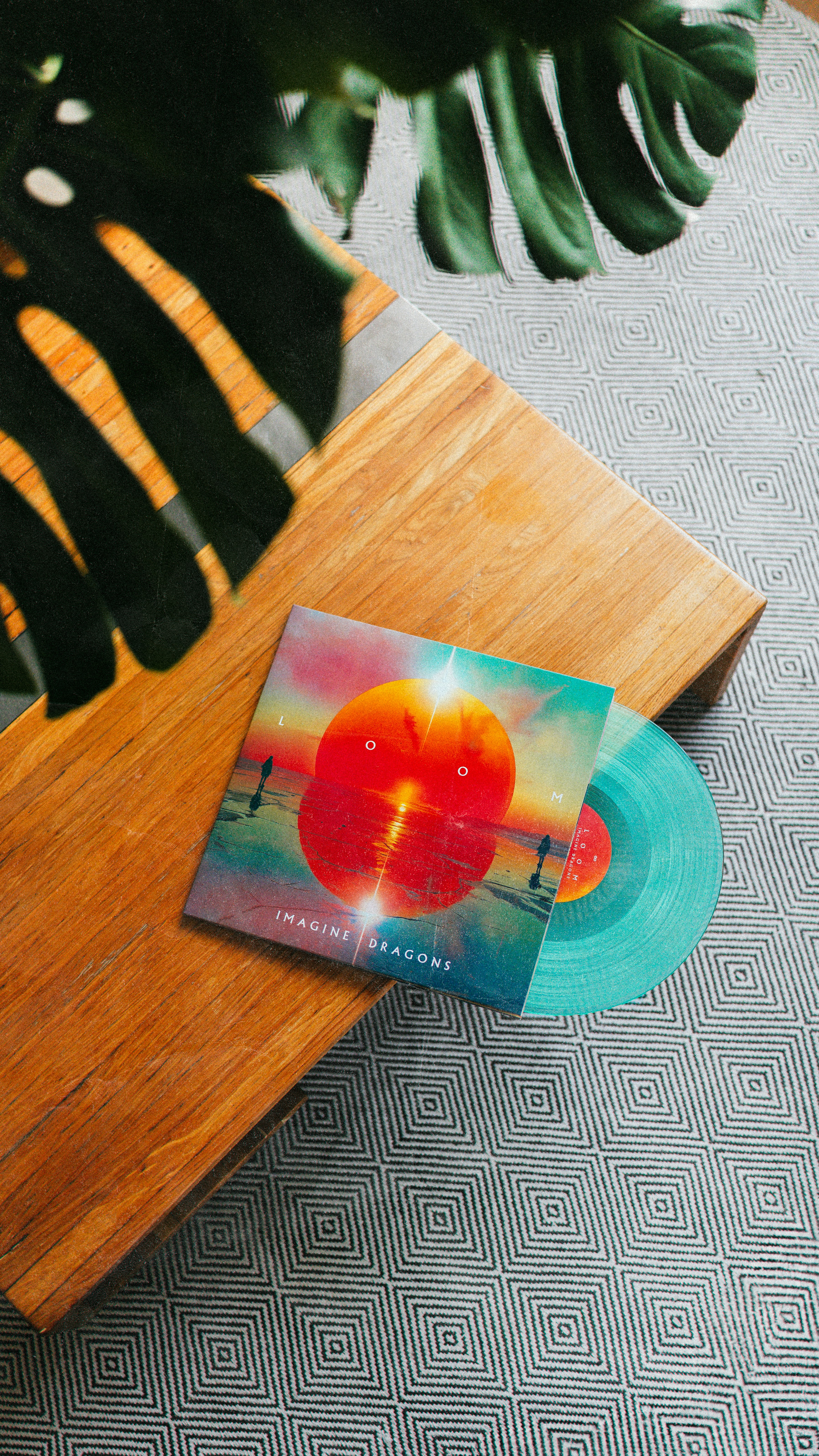A record sitting on top of a wooden table next to a plant