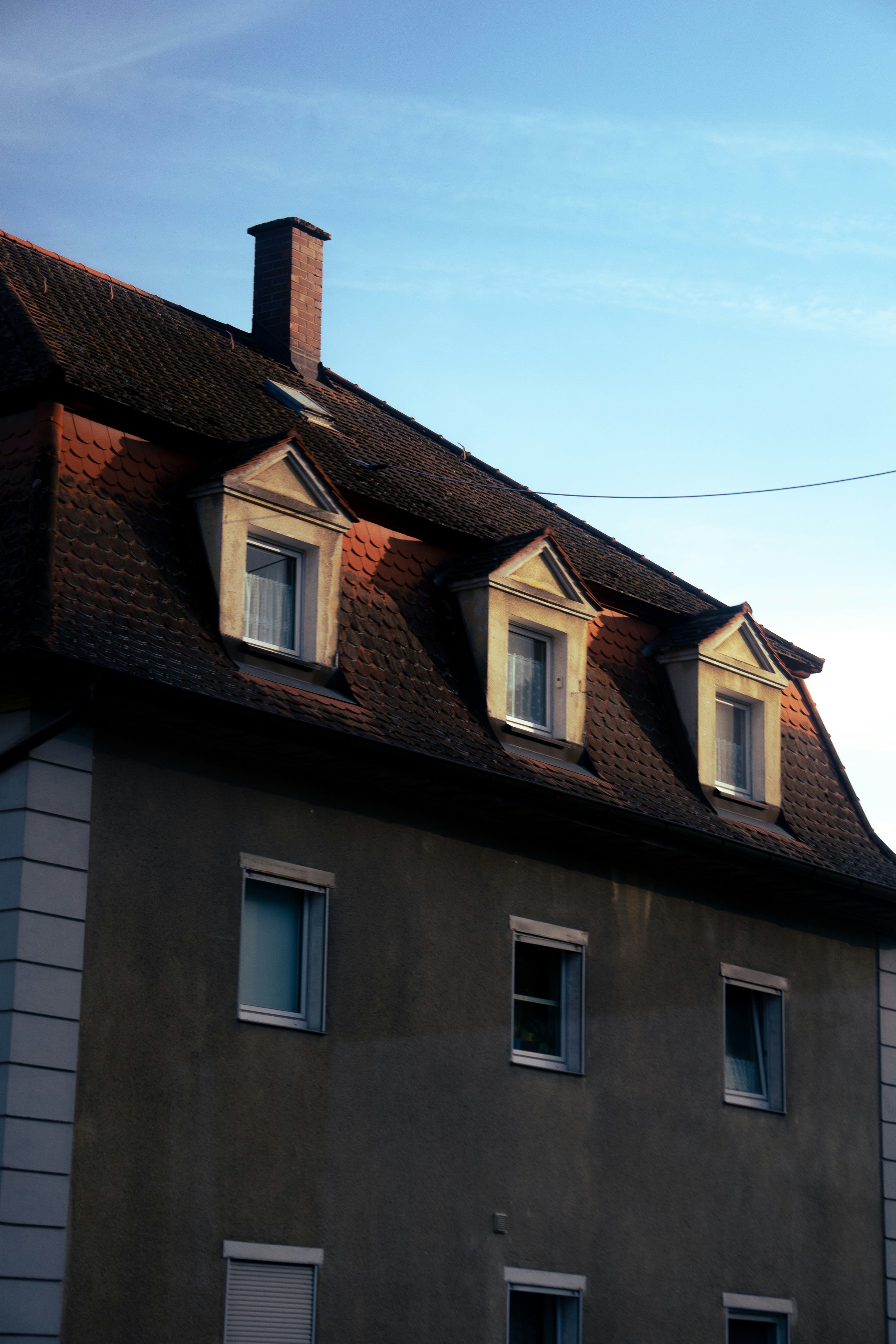 Dormer windows on a tiled roof under blue sky