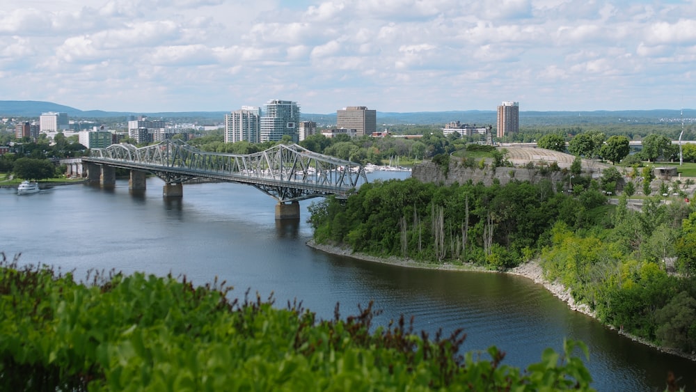 steel bridge, body of water, and city during daytime