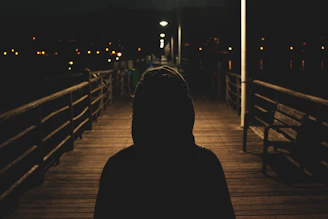 person wearing hooded jacket walking in bridge