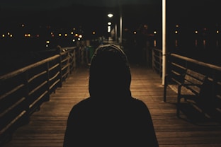 person wearing hooded jacket walking in bridge