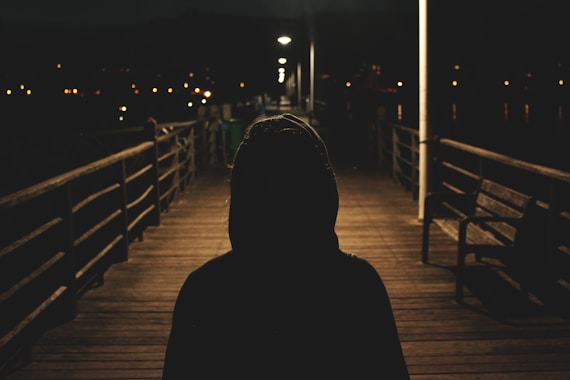 person wearing hooded jacket walking in bridge