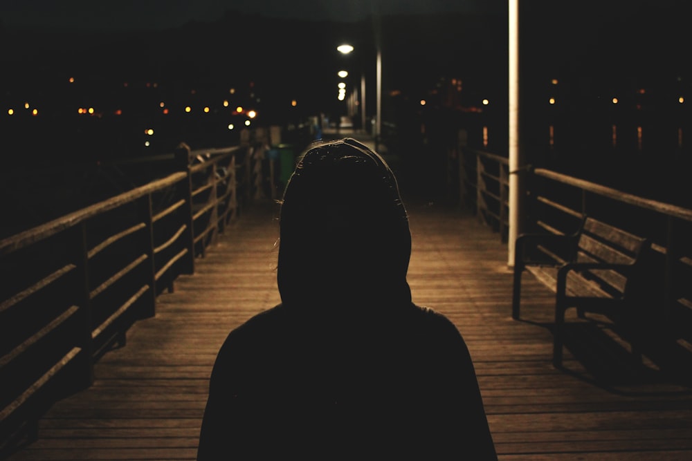 Persona che indossa una giacca con cappuccio che cammina nel ponte