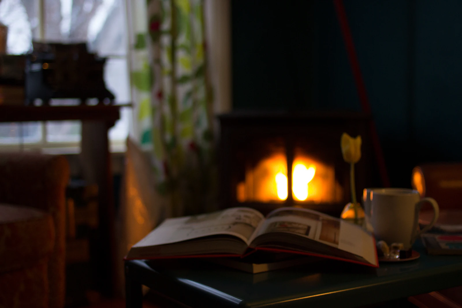 Fauteuil de lecture éclairé par une bougie, plaid en laine et livre ouvert