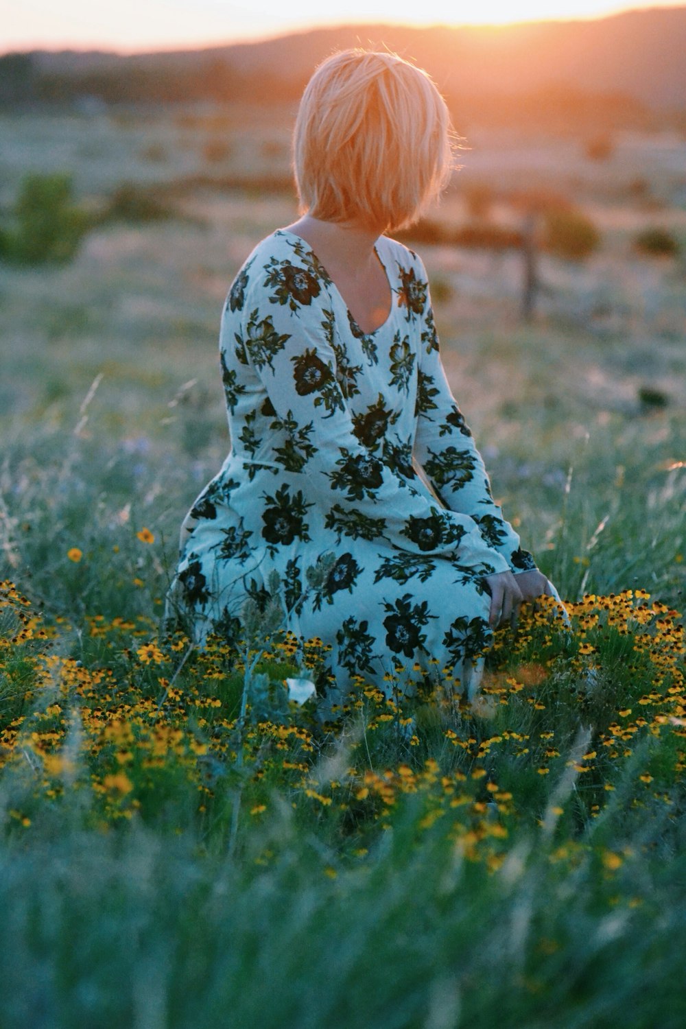 Femme assise sur le champ de fleurs jaunes pendant la journée